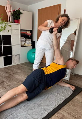 Krankengymnastik/Physiotherapie in Göppingen-Bartenbach. Patient übt mithilfe von Dietlinde Liptaks Anleitung eine Übung aus, die ihm von Physiotherapeutin und Krankengymnastik-Expertin Dietlinde Liptak in der PhysioCranio Privatpraxis Dietlinde Liptak gezeigt wird.