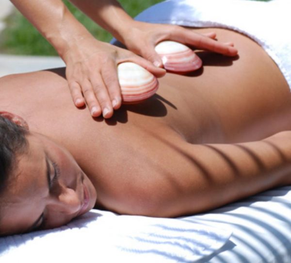 Eine Patientin wird in diesem Bild mit der Hot Shell Massage der PhysioCranio Privatpraxis Dietlinde Liptak in Göppingen - Bartenbach behandelt. Dabei kommen Venusmuscheln zum Einsatz, die bei der Hot Shell Massage essenziell und wohltuend sind.